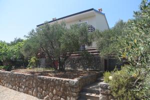 a house with a stone wall and a tree at Garden Apartment Braut in Kornić