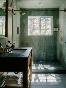 uma casa de banho com um lavatório e um chuveiro com azulejos verdes em Dawn Ranch em Guerneville
