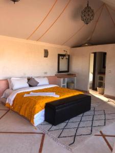 a bedroom with a large bed with an orange blanket at Desert Luxury Camp in Mhamid