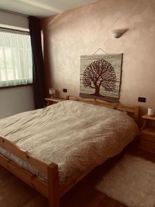 a bedroom with a bed with a tree picture on the wall at Appartamento El Feudo in Tesero