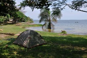 a tent sitting on the grass next to the water at Banda Island Resort and Campsite in Kalangala