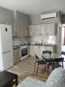 a kitchen with a table and chairs and a white refrigerator at Vasiliki Studios Tolo in Tolo