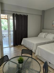 a hotel room with two beds and a glass table at Vasiliki Studios Tolo in Tolo