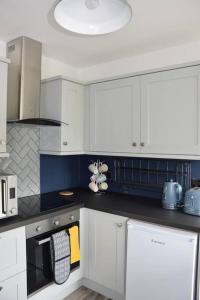 a kitchen with white cabinets and a stove top oven at Cosy Coastal Cottage in Portballintrae in Portballintrae