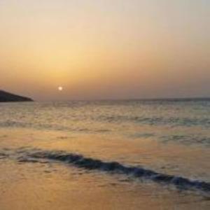 a sunset on a beach with the ocean at Ghougine Serenity Residence Bis in Tangier