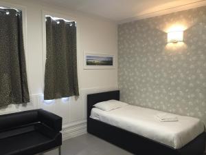 a hotel room with a white bed and a white wall at Paddington Apartments in London