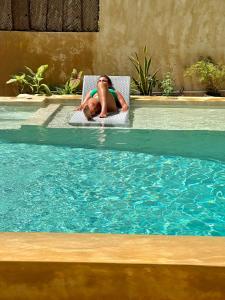 a woman sitting in a chair in a swimming pool at Chikachika Beach B&B in Nungwi