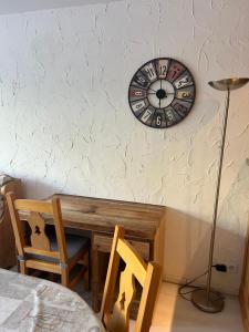 eine Uhr an einer Wand mit einem Tisch und einem Stuhl in der Unterkunft Tignes le Lac - Appartement au pied des pistes in Tignes