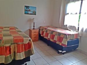 a bedroom with two beds and a dresser and a window at RIVIERA-CASA FAMILIAR PERTO DA PRAIA-3 QUARTOS-3 BANHEIROS-ATÉ 10 PESSOAS-Módulo 4 in Bertioga