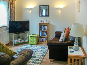 a living room with a couch and a tv at The Old Store in Onich