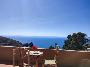 een tafel en stoelen op een balkon met uitzicht op de oceaan bij Hosteria LAS ISLAS in Comunidad Yumani