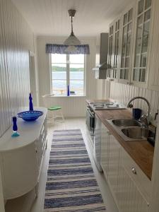 a white kitchen with a sink and a counter at Waterfront house with jacuzzi & jetty in Stockholm in Stockholm