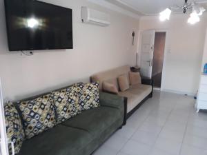 een woonkamer met een bank en een flatscreen-tv bij SARIMSAKLI PLAJINA 0 METRE DENİZ MANZARALI LÜX DAİRE in Ayvalık