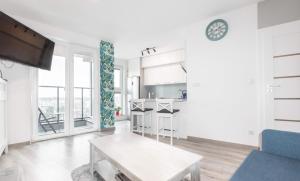 a white living room with a table and a kitchen at Apartament BeAndGo Aleja 29 Listopada in Krakow