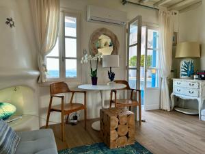 a living room with a table and chairs and windows at C Bay in Mýkonos City