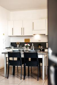 una cucina con tavolo, sedie e armadietti bianchi di Casa R&R *10' a Piedi da Piazza Del Campo*! a Siena