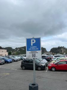 een bord op een parkeerplaats met geparkeerde auto's bij La Capilla in Ribadesella