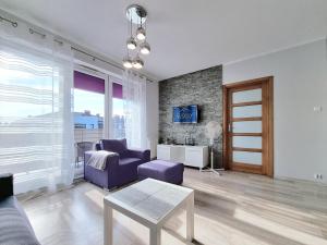 - un salon avec un canapé violet et une fenêtre dans l'établissement CLASSY APARTMENTS - AQUAPARK Reda, à Reda