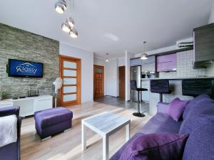 - un salon avec un canapé violet et une table dans l'établissement CLASSY APARTMENTS - AQUAPARK Reda, à Reda