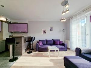 sala de estar con sofá púrpura y TV en CLASSY APARTMENTS - AQUAPARK Reda, en Reda