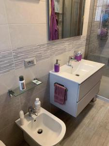 bagno bianco con lavandino e specchio di Appartamento Michelangelo a Novara