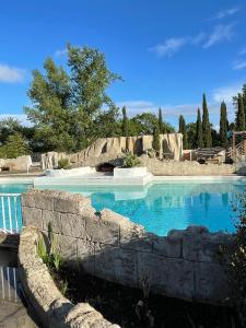 a swimming pool with blue water and a stone wall at gîtes Studio de tourisme du Domaine Piscine Spa Balnéo in Lescout