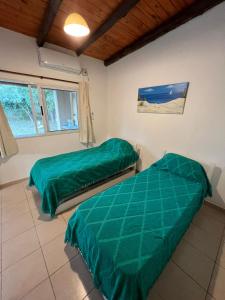 2 camas en una habitación con sábanas verdes en Olivares de Krishna en San Fernando del Valle de Catamarca