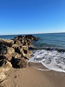 una playa con rocas y el océano en un día soleado en Mon Appart à la plage, piscine, wifi, tv + Netflix, en Frontignan