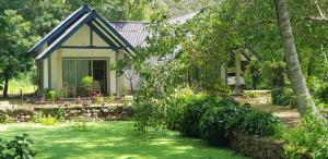 una pequeña casa con un jardín frente a ella en The Croft Sri Lanka, 