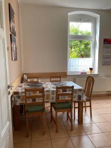 ein Esszimmer mit einem Tisch, Stühlen und einem Fenster in der Unterkunft Ferienwohnung Martina in Blankenburg