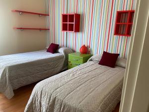 2 camas en una habitación con paredes a rayas en apartamentos beach langosteira 2 en Finisterre