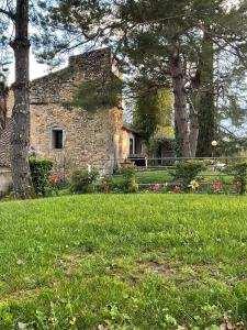 una casa de piedra con dos árboles y un campo de hierba en gîtes Studio de tourisme du Domaine Piscine Spa Balnéo en Lescout