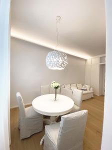 a white dining room with a white table and chairs at The window on the theatre and the cathedral - Luxury apartment in Como