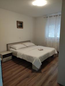 a white bedroom with a bed and a window at Holiday Home Luma in Grabovica