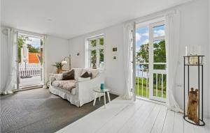 2 Bedroom Amazing Apartment In Svaneke في سفانيكي: غرفة معيشة بيضاء مع أريكة ونوافذ