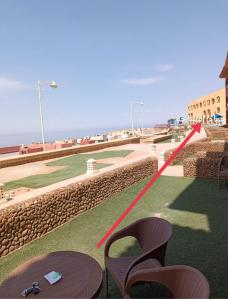 uitzicht op een golfbaan met stoelen en het strand bij الحدائق المعلقة المصطبة الخامسة بورتو السخنة للعائلات فقط in Ain Sokhna