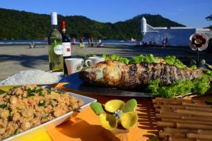 einen Tisch mit einer Mahlzeit und einer Flasche Wein in der Unterkunft Praia Guaratuba Costa do Sol - 600mt da praia in Bertioga + 28 Fotos
