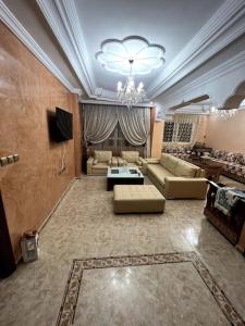un ampio soggiorno con divani e lampadario a braccio di Appartement familiale méditerranéen ad Al-Ḥoseyma