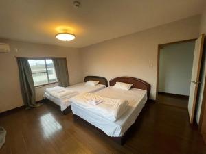 two beds in a room with a window at 高島市一棟貸切 グループファミリーok Biwa Lake琵琶湖 徒歩10分 大人数でご利用だとお得連泊がお得BBQ可能自転車無料利用可 in Takashima