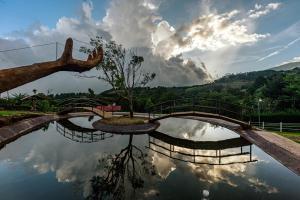un puente sobre un estanque con un reflejo en el agua en Hotel & Spa Escondite de la Montaña en Sabana Redonda