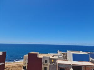 a building on the beach with the ocean in the background at Appartement de vacances in Larache