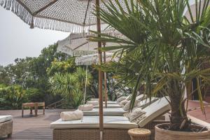um pátio com um monte de cadeiras e um guarda-sol em Villa Pietra Estoril Eco Guesthouse em Estoril