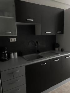 a kitchen with black cabinets and a sink at Souzana Suite Leptokarya in Leptokarya +2 photos