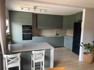 una cocina con armarios azules y 2 taburetes blancos en Spacious 4 bedroom with garden - Central location en Gotemburgo