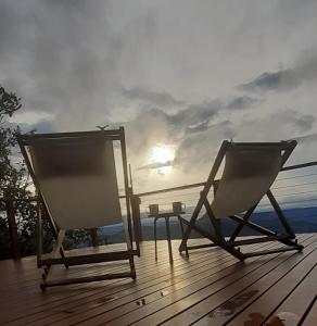 two chairs sitting on a deck with the sun in the background at Recanto Ninho das Aguias in Nova Petrópolis