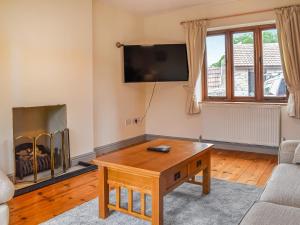 a living room with a coffee table and a fireplace at Swift Cottage in Chilton Polden 