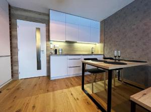 una cocina con mesa de madera y una cocina con armarios blancos. en Apartmán Harmonie - Šumava en Frischwinkel