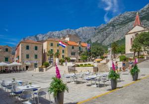 a town with tables and chairs and mountains in the background at Ellamar City Center Apartment 2 in Makarska