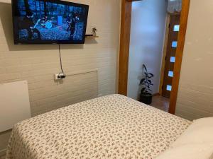 1 dormitorio con 1 cama y TV en la pared en Alojamiento Sandra - Habitación 02 en Villarrica