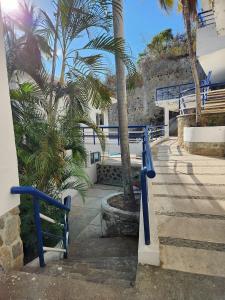 a blue railing next to a building with palm trees at Secretos del Sol Acapulco villas a 5 minutosdel mar in Acapulco